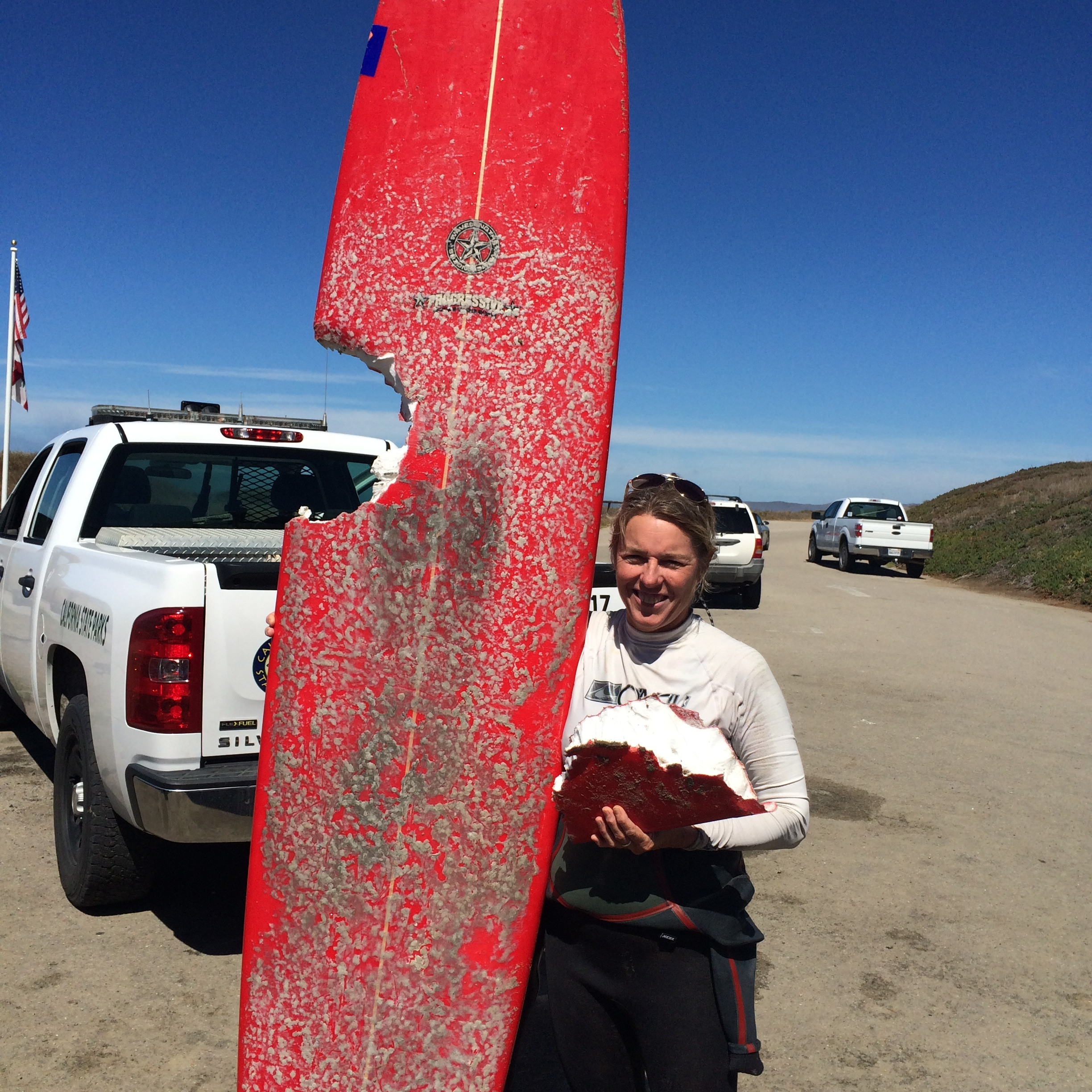 Elinor Standing Holding Surfboard with Shark Bite